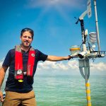 Ed Verhamme of LimnoTech standing with environmental data buoy