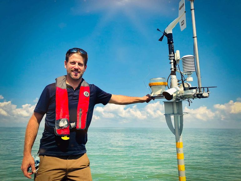 Ed Verhamme of LimnoTech standing with environmental data buoy