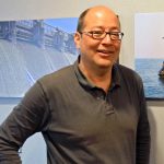 Tad Slawecki standing in front of project photos at the LimnoTech Ann Arbor office.