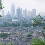 View of Zhenjiang, China with tall buildings in the background and smaller homes at the forefront