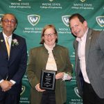 Carrie Turner stands in the middle of Dr. Ali Abolmaali, Dean of the College of Engineering (left), and Dr. William Shuster, Professor and Chair of the Civil and Environmental Engineering Department (right) holding an award for the Distinguished Engineer for the Civil and Environmental Engineering Department at the Wayne State University College of Engineering 2024 Hall of Fame