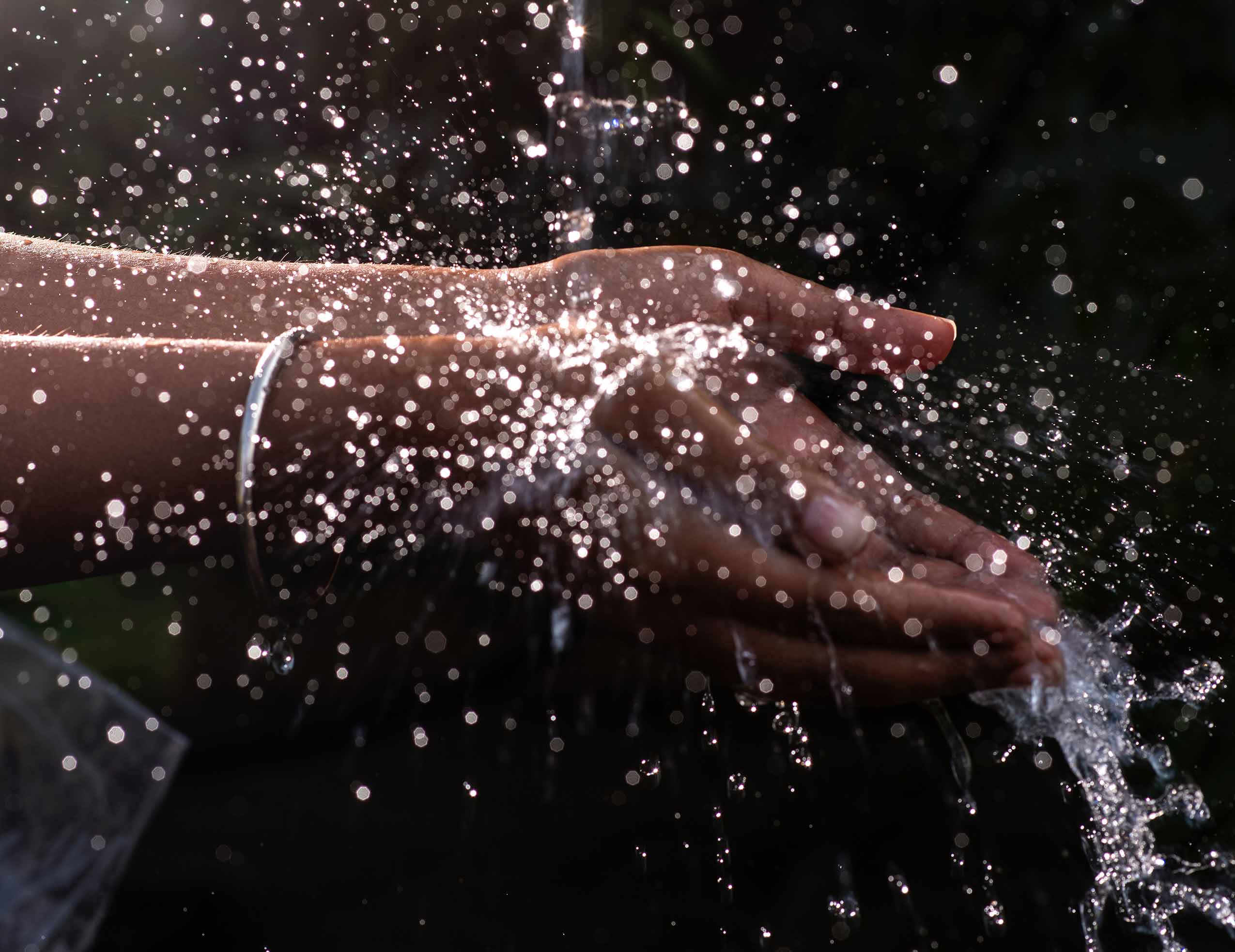Water splashing on hands with a dark background.