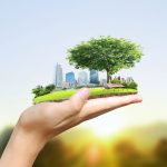 Hand holding a city with a park in the forefront.