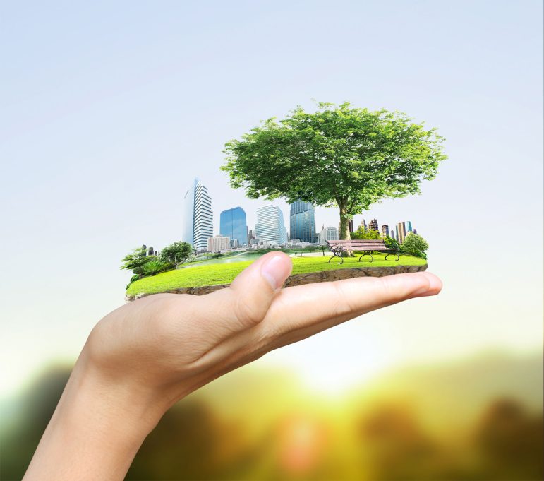 Hand holding a city with a park in the forefront.