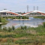 Toronto Port Lands, Don River, Biidaasige Park, showing a bridge over the river with vegetation and rocky shores surrounding the water.