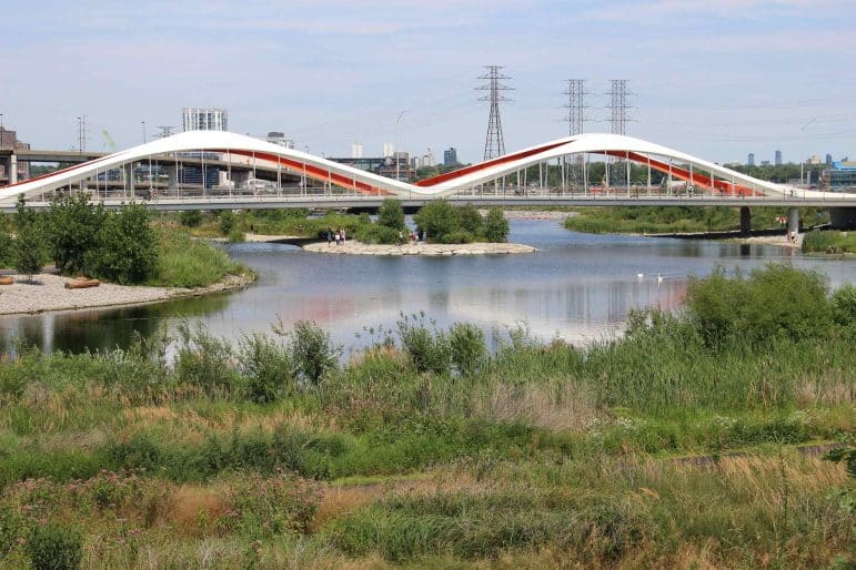 Toronto Port Lands, Don River, Biidaasige Park, showing a bridge over the river with vegetation and rocky shores surrounding the water.