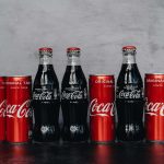 Coca-Cola cans and bottles lined up on a counter.