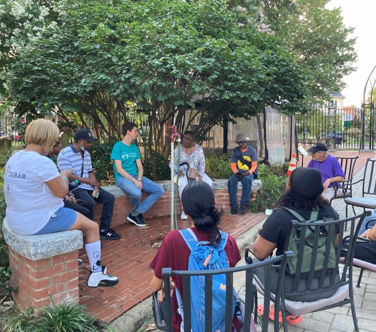 A group of people sitting in a circle in a city environment discussing green infrastructure projects.